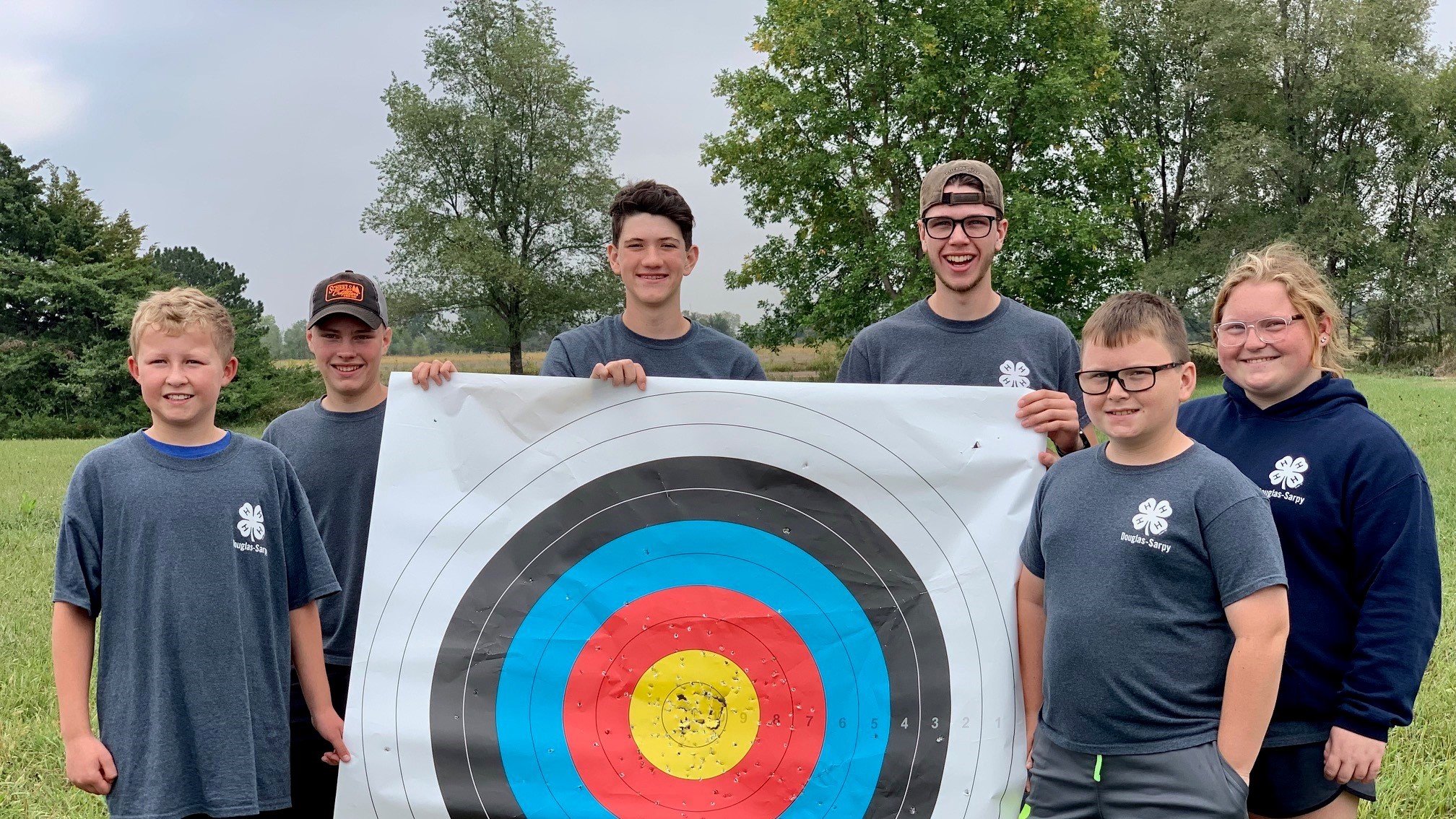 Six 4-H members holding a target at an archery contest.