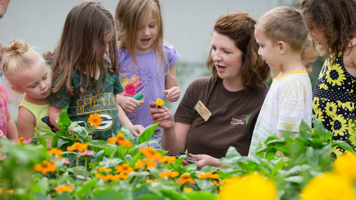 Woman teaching children about plants in a flower garden.