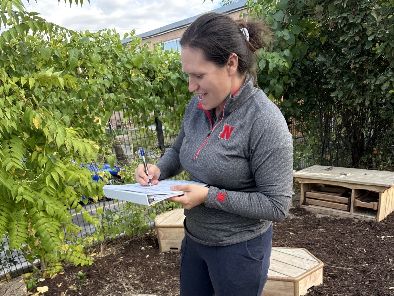 Woman writing on a notebook outside in a children's play area.