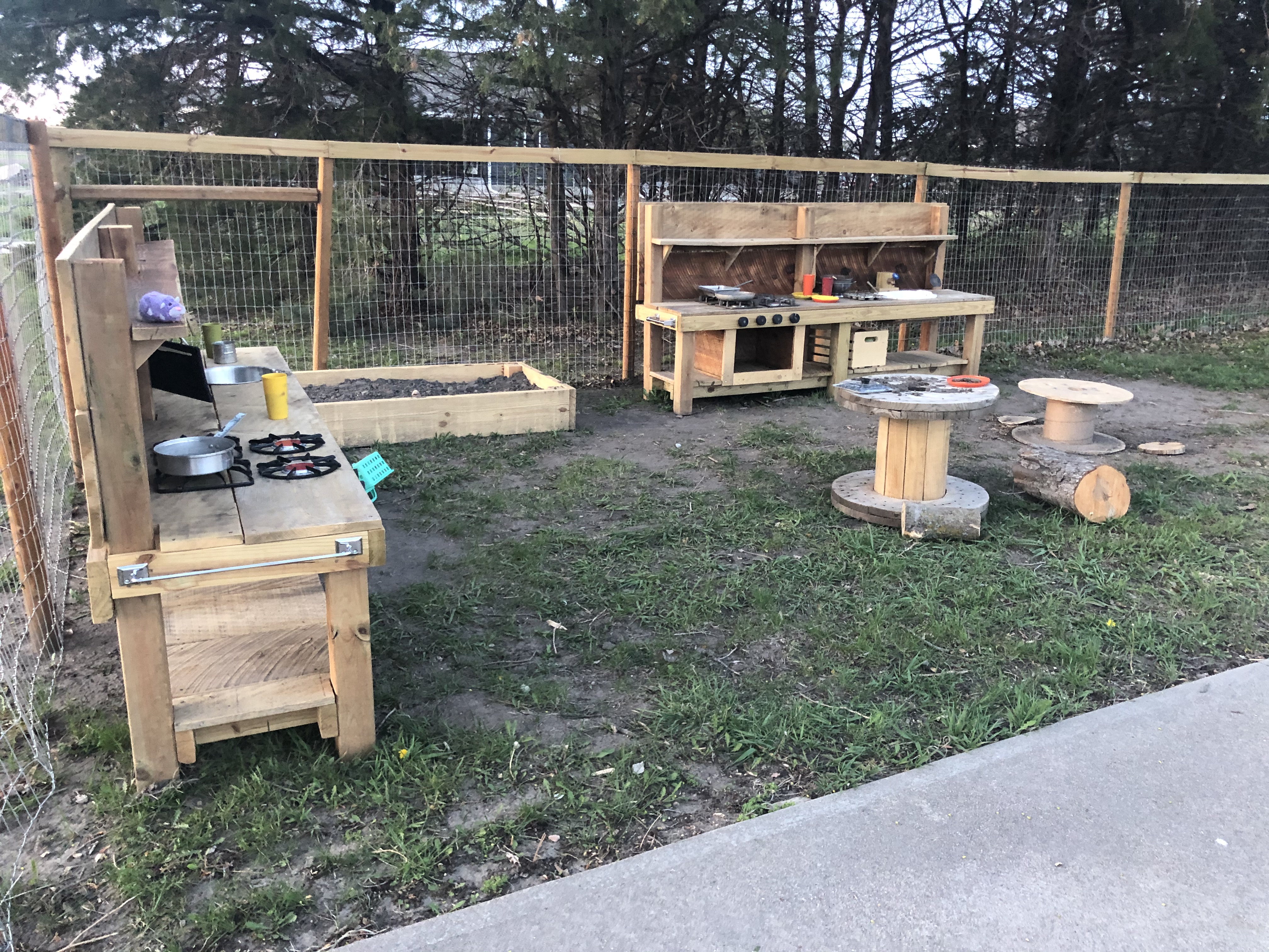 Outdoor play area for children with two play kitchens and tables.