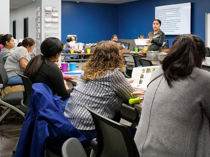 Adult woman teaching a group of adult women a SNAP-Ed food preservation class. 