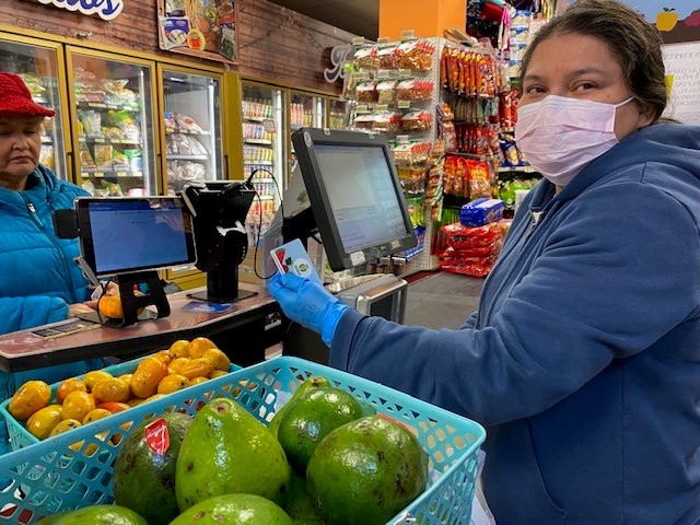 A female cashier excepting payment from a woman for groceries at a grocery store.