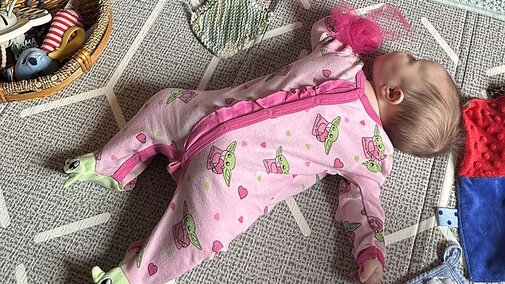 Infant lying on floor.