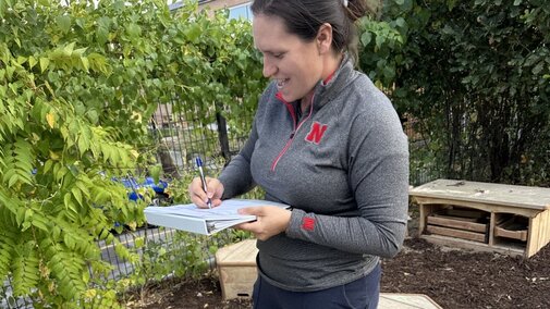 Woman writing on a notebook outside in a children's play area.