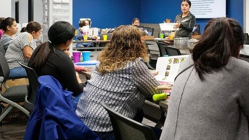 Adult woman teaching a group of adult women a SNAP-Ed food preservation class. 