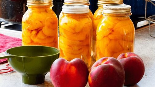 Image of canning jars, a funnel, and apples.