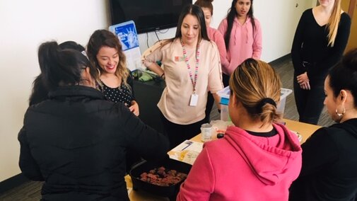 A group of women watching a cooking demonstration.