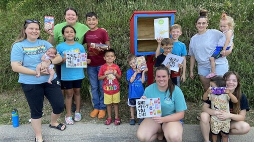 Adults and children in front of a little free pantry.