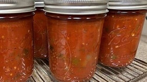 Jars of salsa on a metal rack.