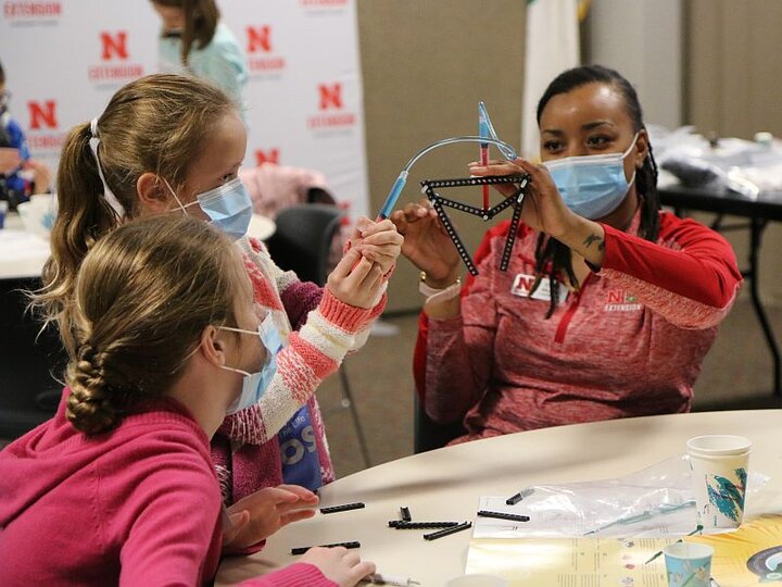 A woman teaching two girls at a table about structures.