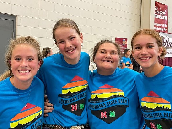 Four smiling girls wearing Nebraska State Fair 4-H t-shirts.