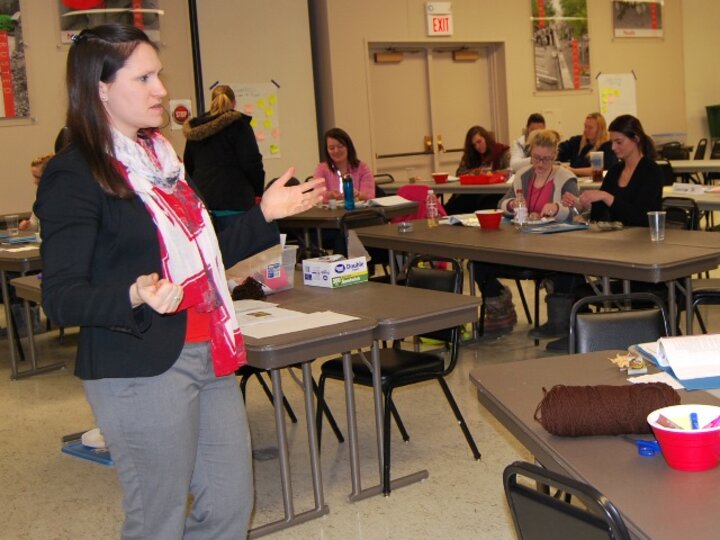 Woman standing teaching a class of adults.